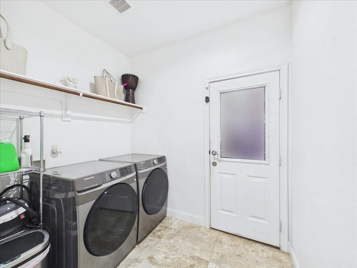 Built-in shelving with hanging rod, tile flooring, and exterior access door with frosted glass panel