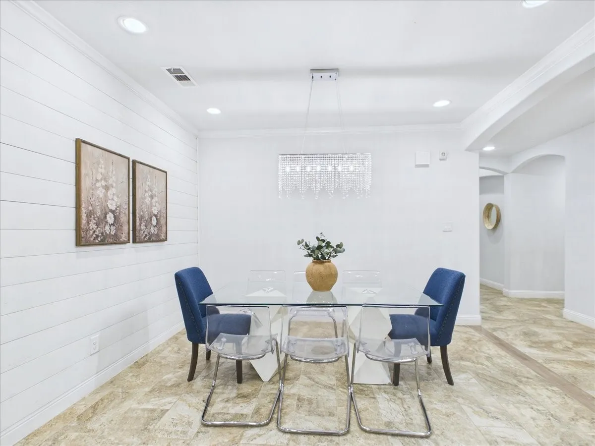 Recessed lighting, shiplap accent wall, chandelier, arched entryway, and tile flooring