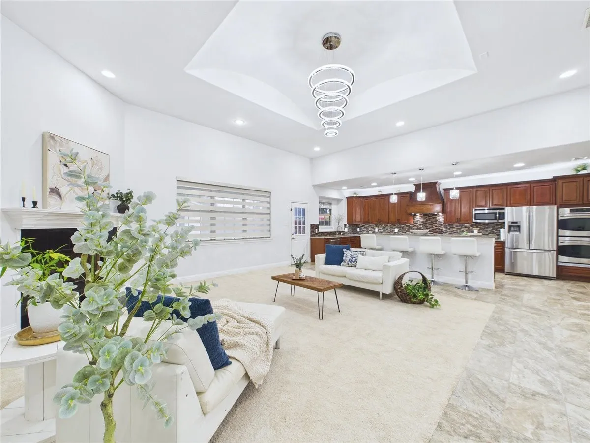 Open-concept living space with a tray ceiling and a multi-ring chandelier