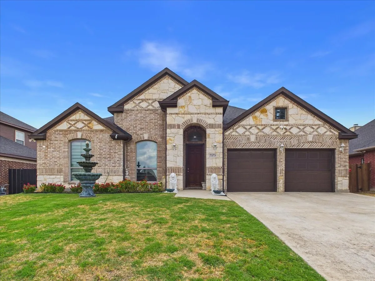 Brick and stone exterior with arched entry, two-car garage, and decorative fountain