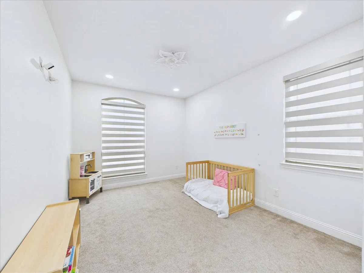 Arched window with striped blinds, recessed ceiling lighting, textured carpeting, and white baseboard molding