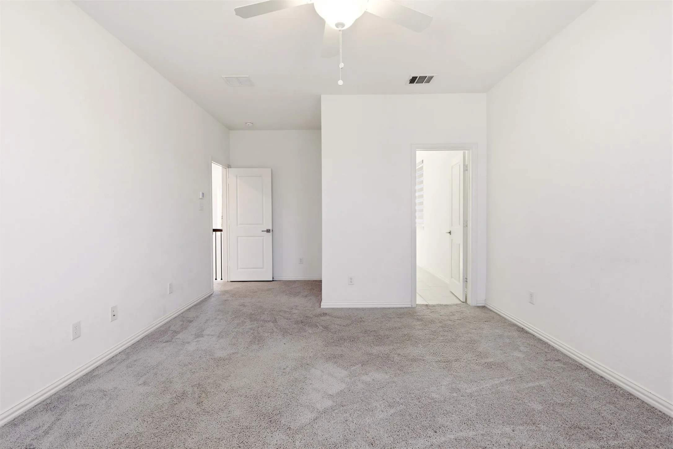 Spacious room featuring neutral carpeting, white walls, a ceiling fan, and white trim