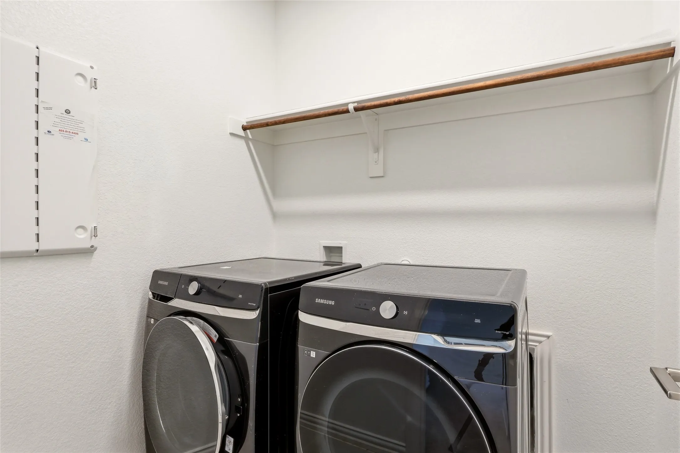 Dedicated laundry space featuring a white wall shelf with a wood-finish hanging rod
