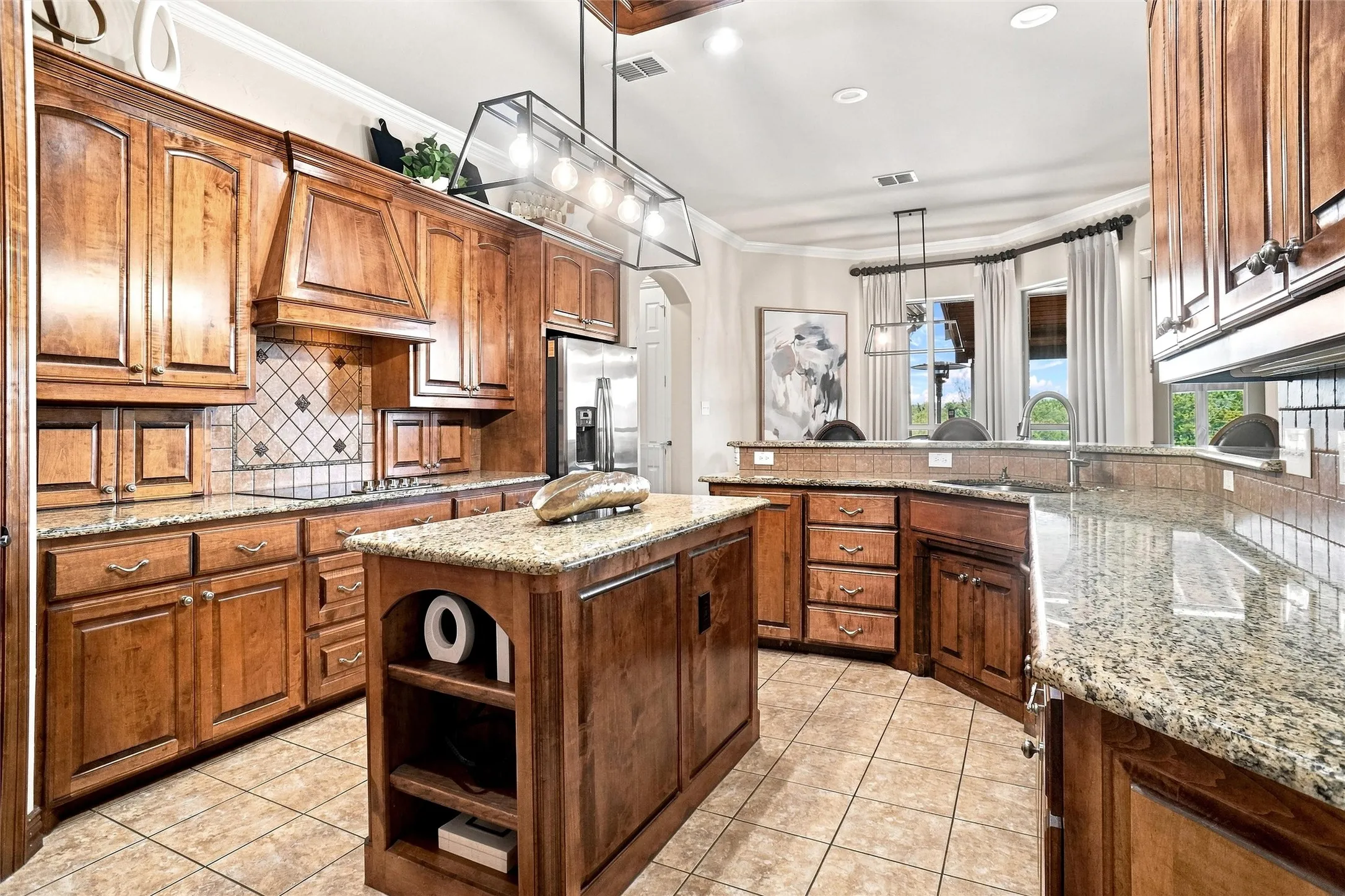 Kitchen featuring extensive wood cabinetry, granite countertops, a central island, a tile backsplash, and stainless steel appliances