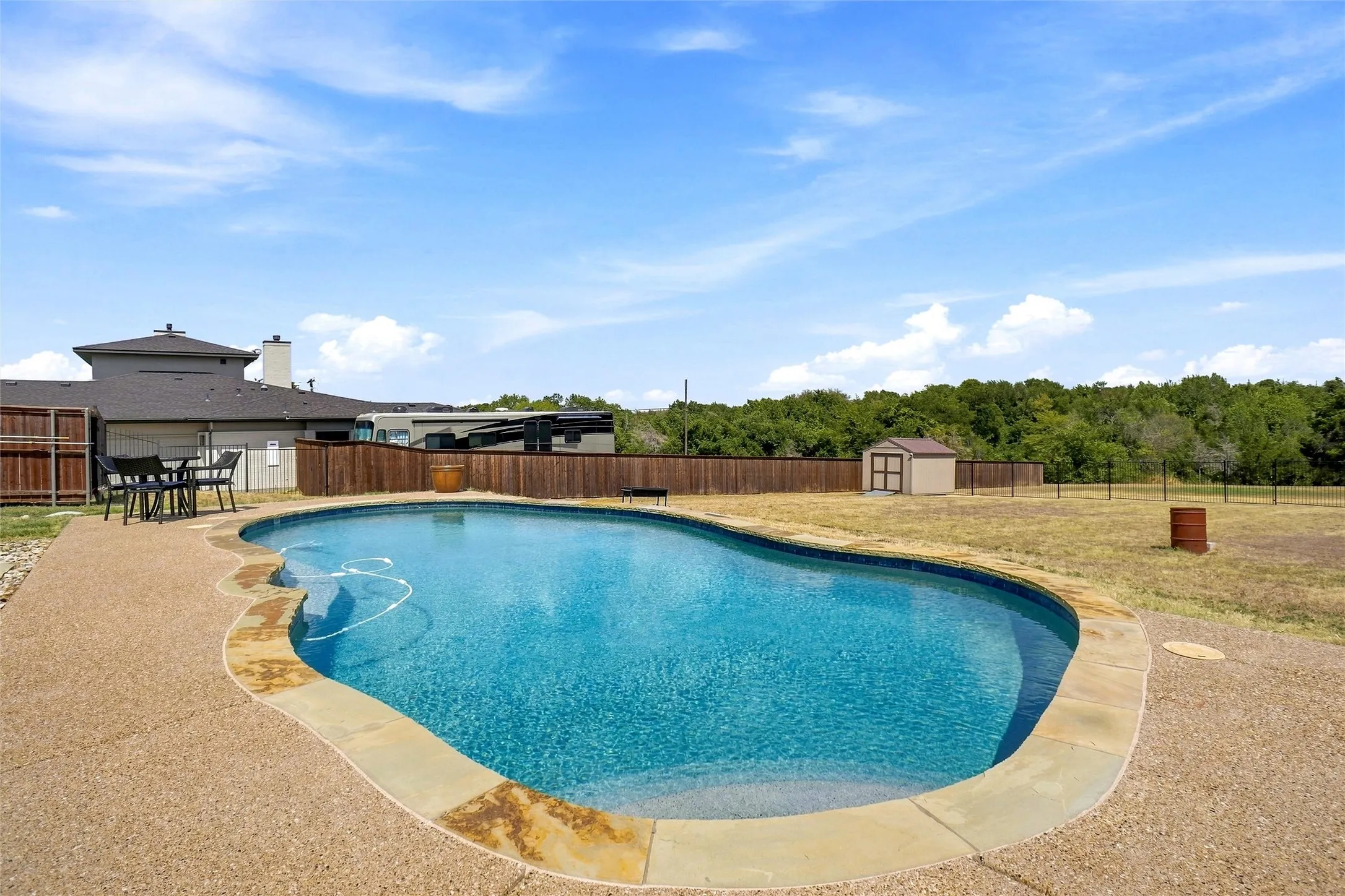 Freeform swimming pool with a surrounding aggregate concrete patio