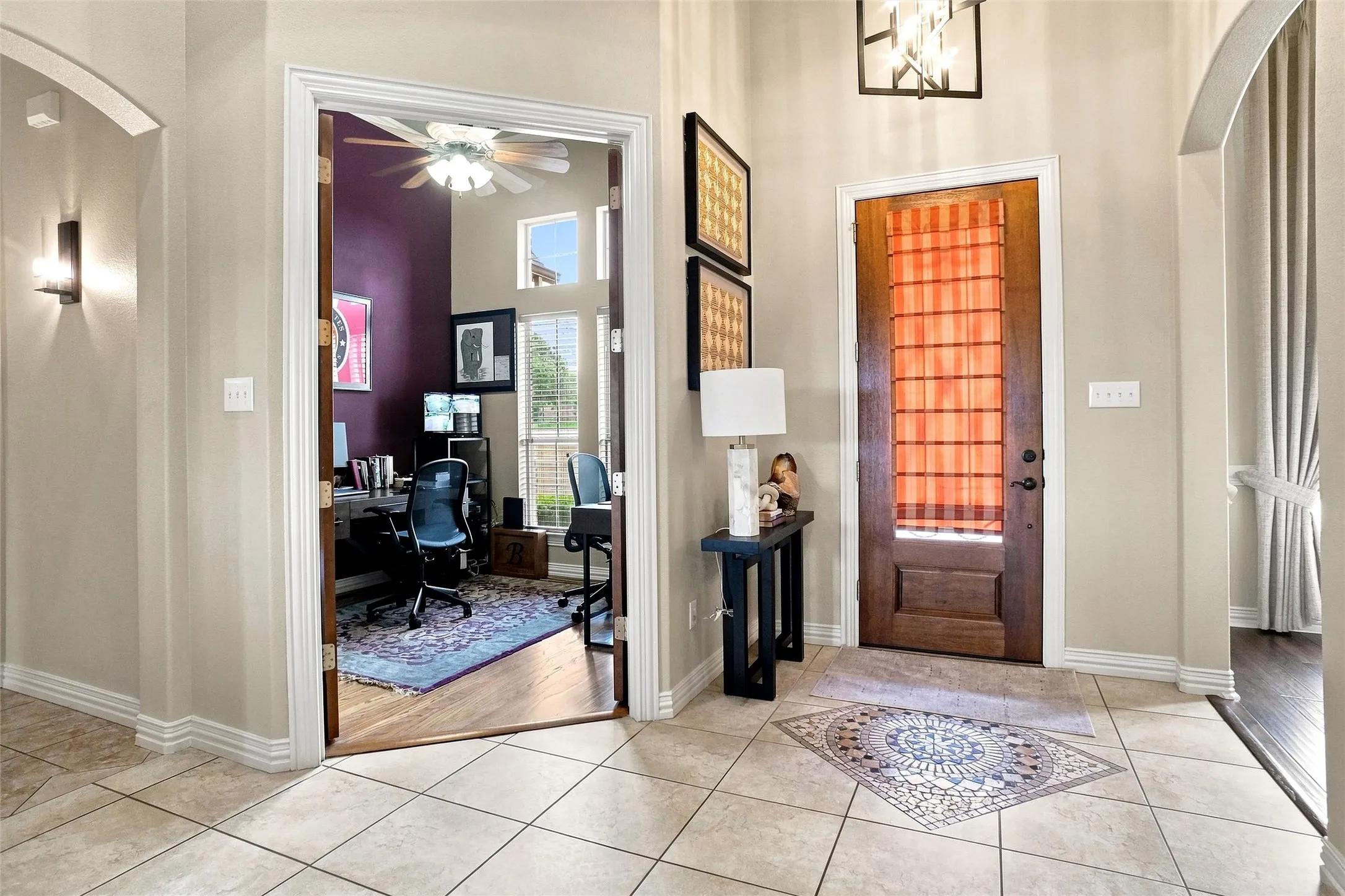 Foyer featuring square tile flooring with a decorative inlay, a wood-panel entry door, and an overhead light fixture