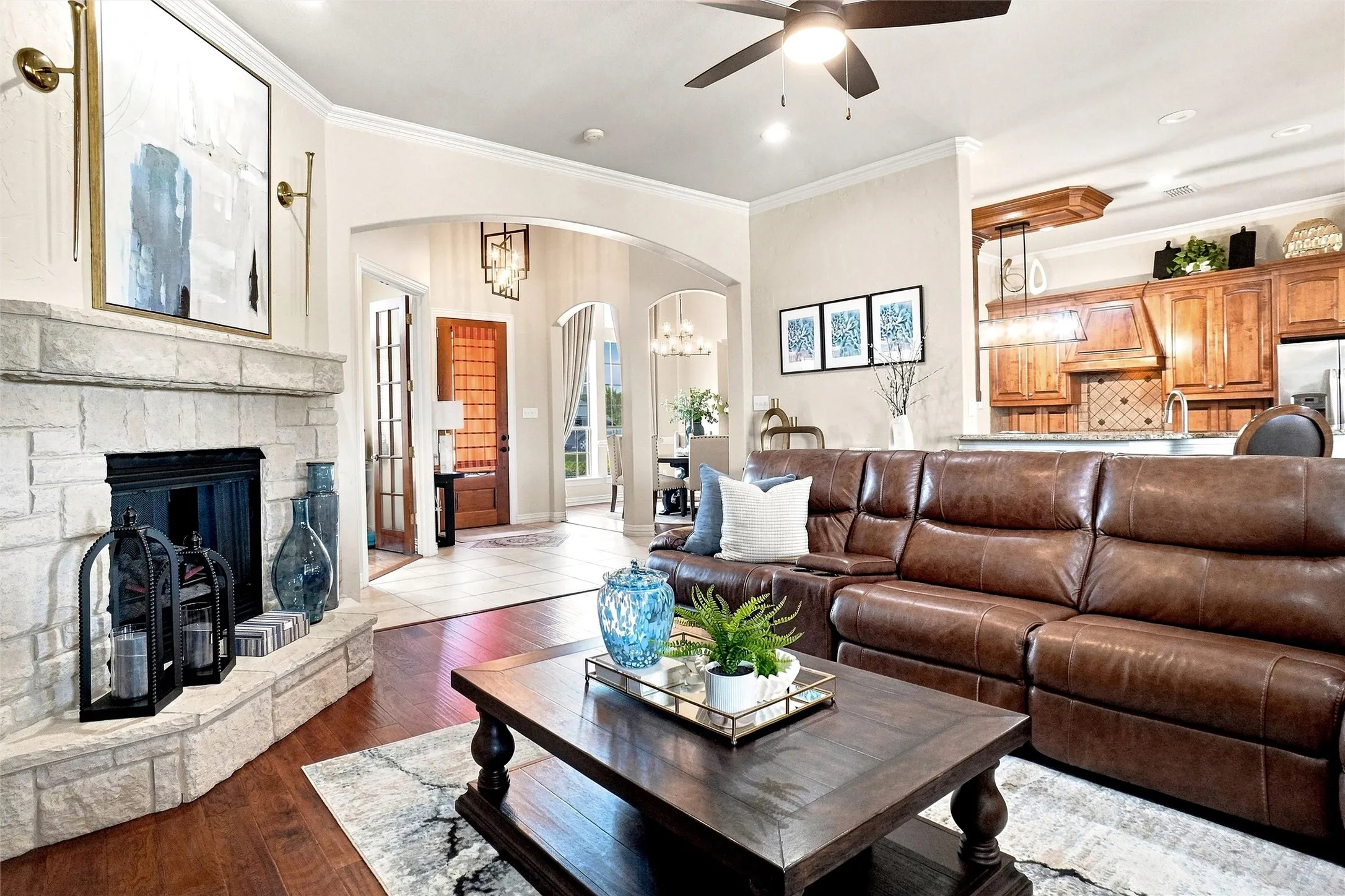 Stone fireplace with a dark firebox, wood-finish flooring, recessed lighting, and an arched entryway