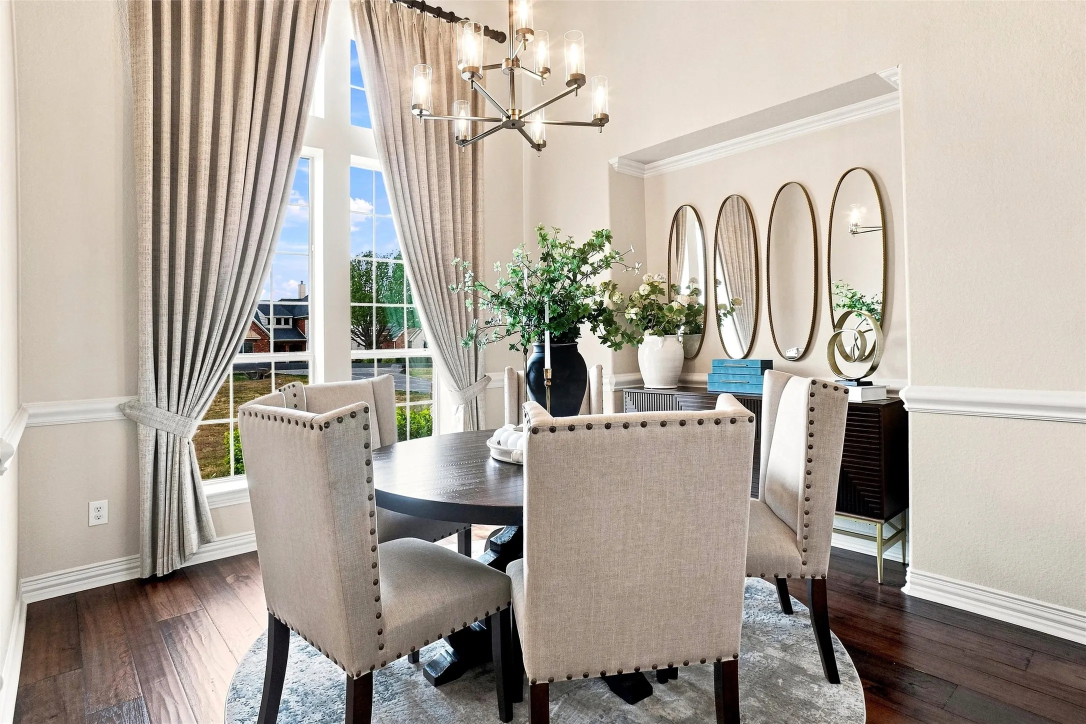 Hardwood-finish flooring, architectural window, chair rail molding, crown molding, and a contemporary chandelier