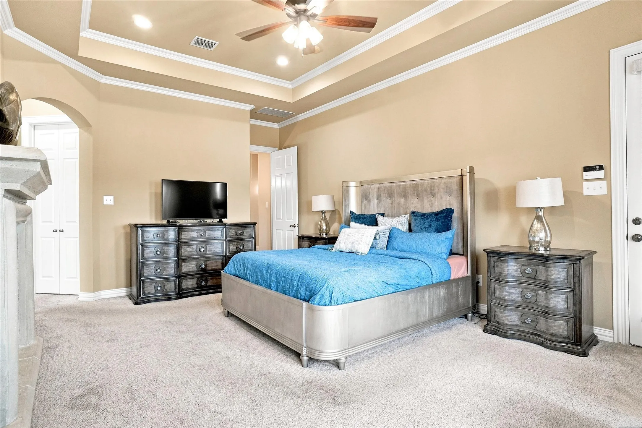 Recessed lighting with a ceiling fan, tray ceiling with crown molding, light-toned carpeting, and a white paneled door