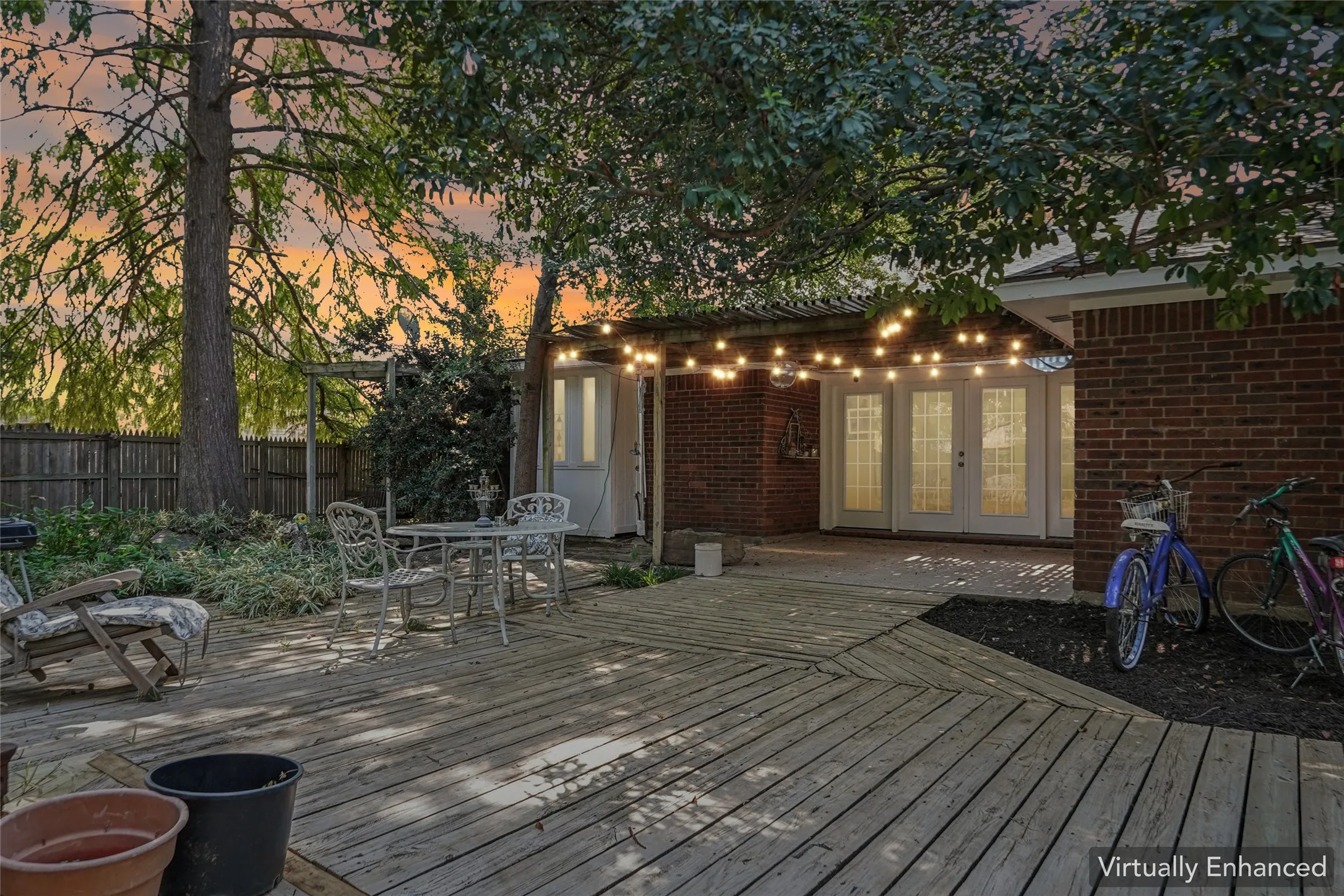 Expansive backyard deck with varied plank orientation, mature trees, brick exterior, and multiple French doors