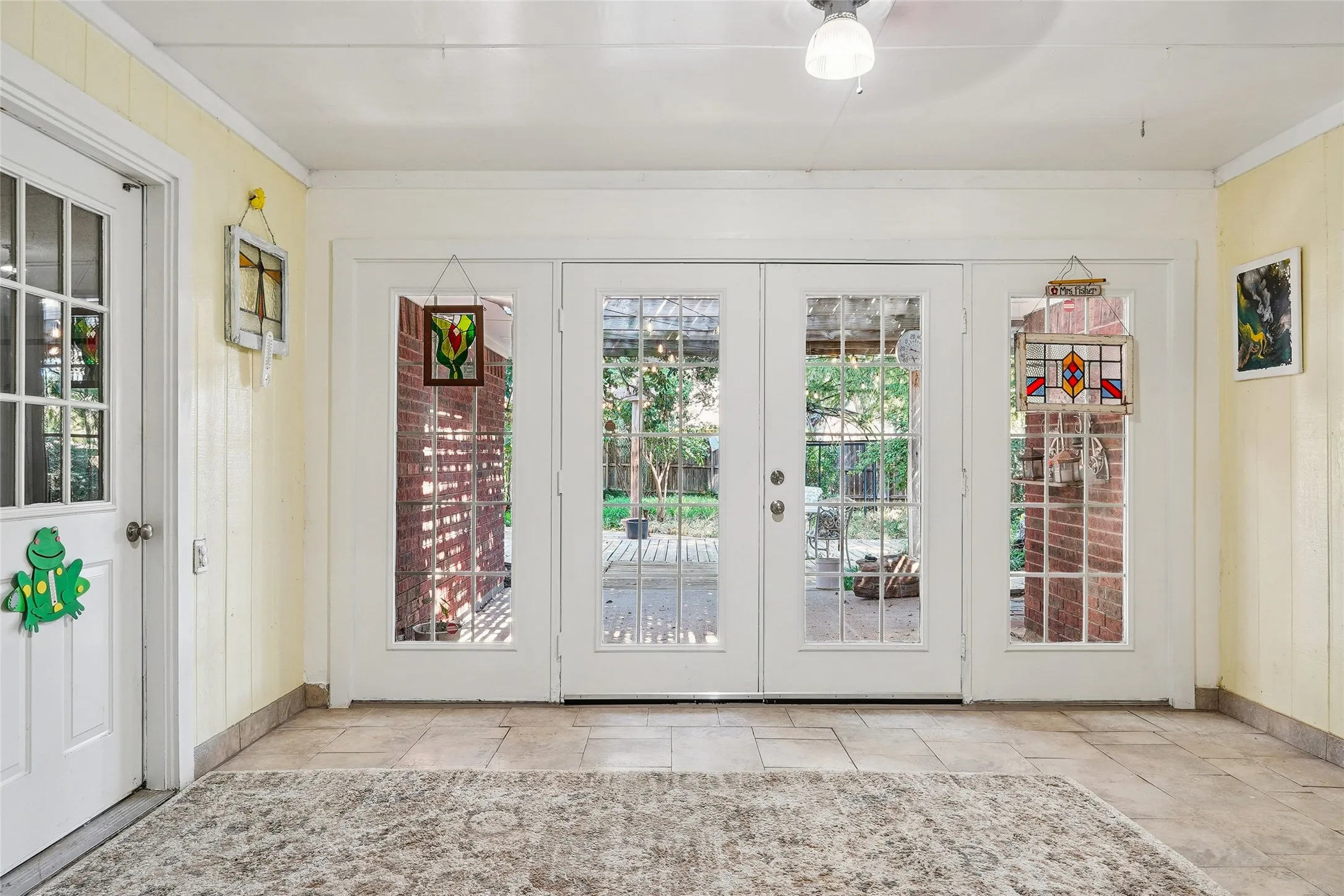 Tile flooring with a neutral finish, multiple white French doors, and a white paneled door with glass inserts