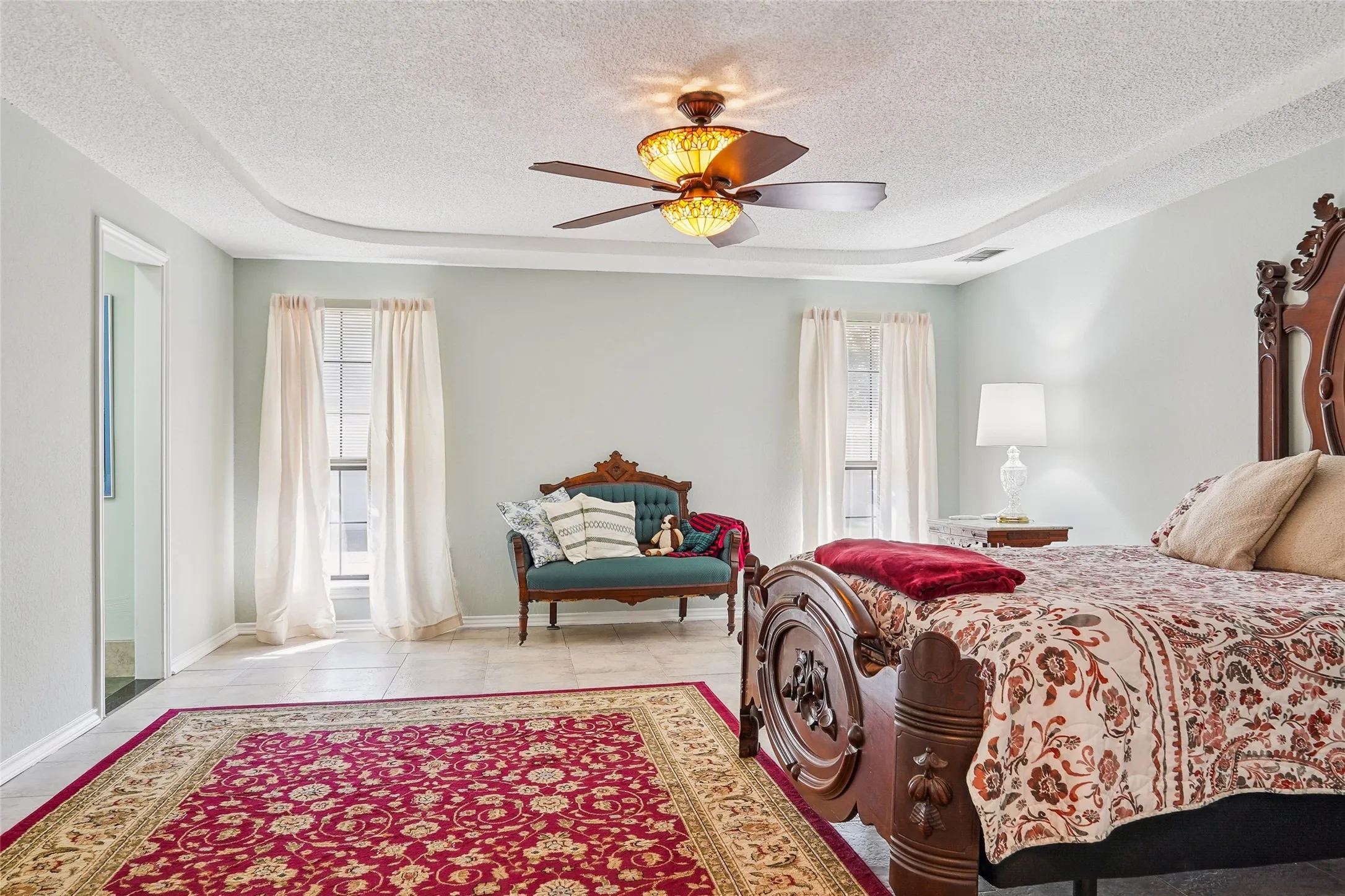 Tray ceiling with recessed lighting and a ceiling fan, tile flooring, and multiple windows for natural light