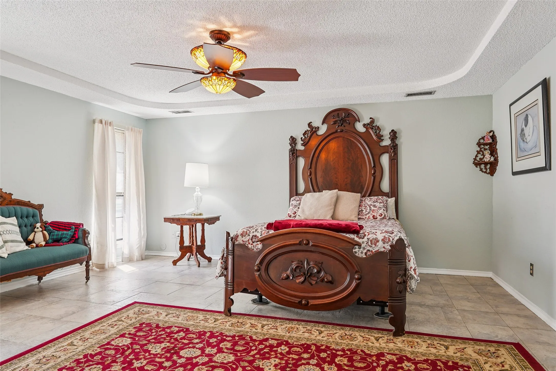 Recessed ceiling with an overhead fan, large window with drapes, and tile flooring