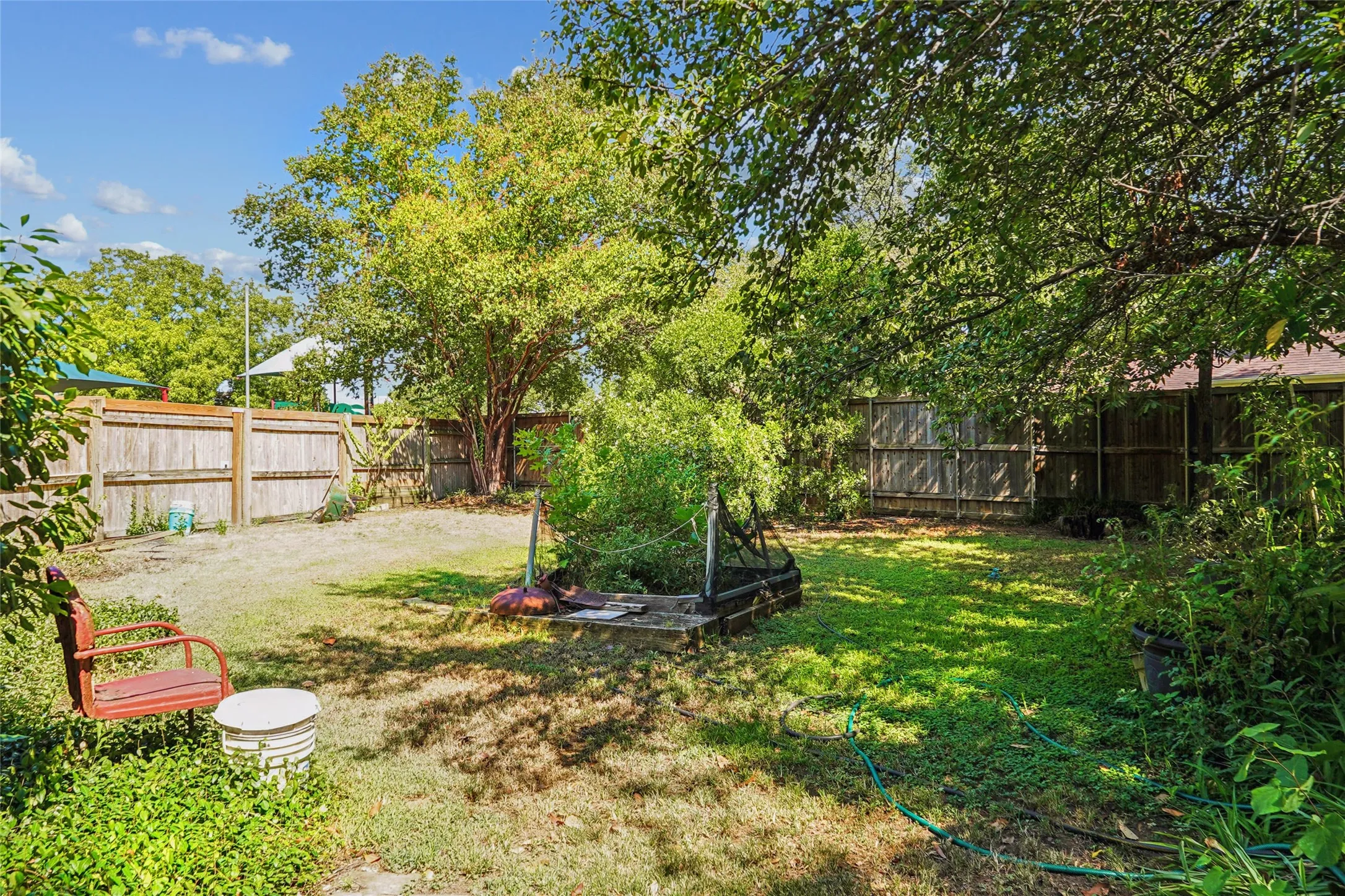Spacious outdoor area featuring a wood fence perimeter and established trees
