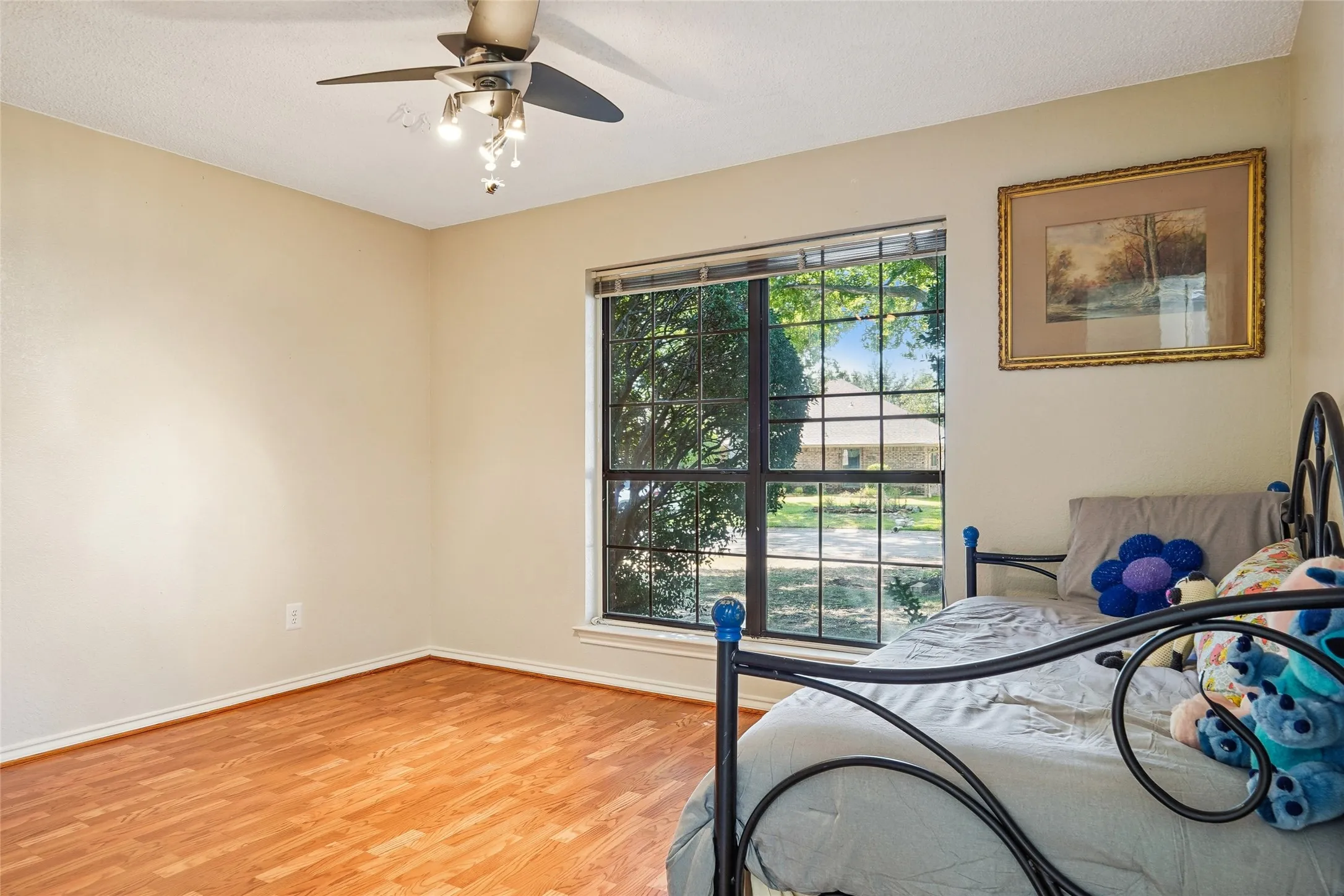 Ceiling fan with integrated lighting, wood-finish flooring, and a large window with grid panes