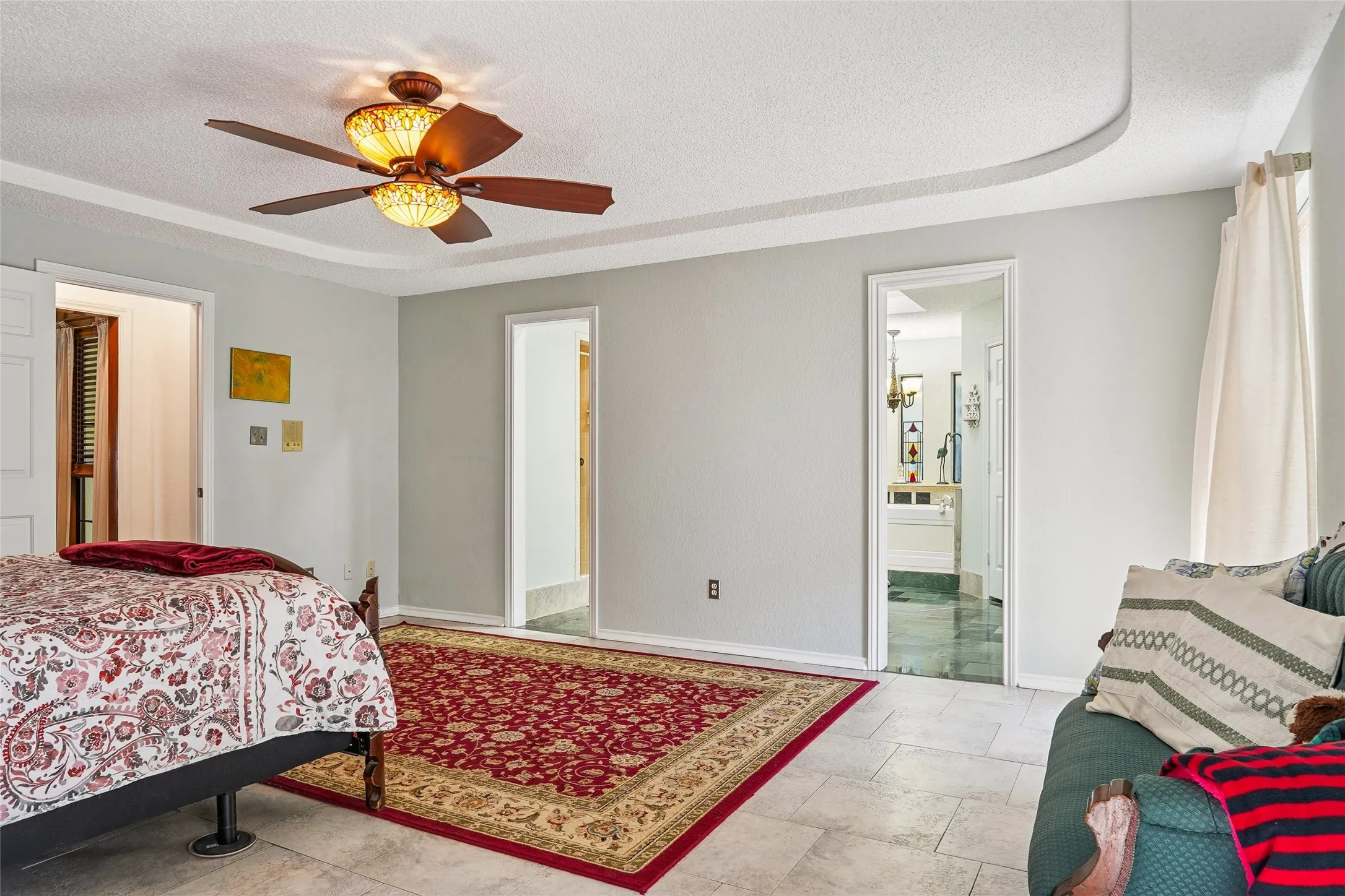 Recessed ceiling detail with crown molding, tiled flooring, and an ornamental ceiling fan