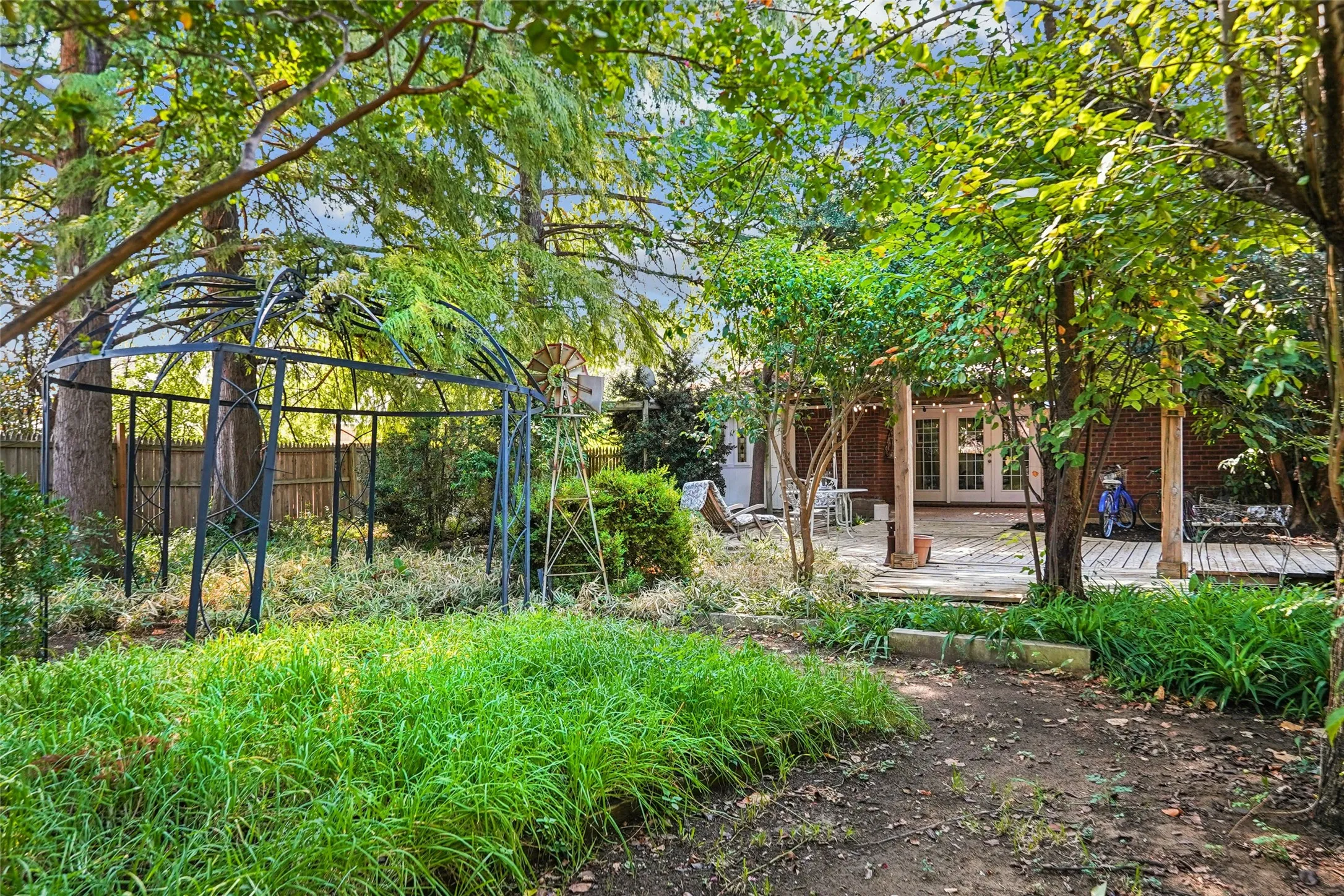 Expansive outdoor space featuring a covered wood deck, brick exterior, and lush mature trees