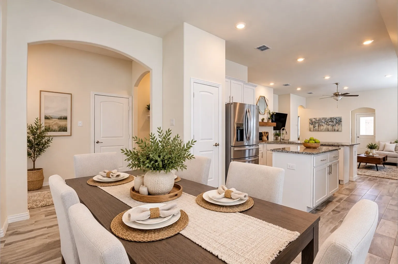 Open-concept living space featuring arched doorways, wood-finish flooring, a kitchen island with stone countertop, stainless steel appliances, and recessed lighting