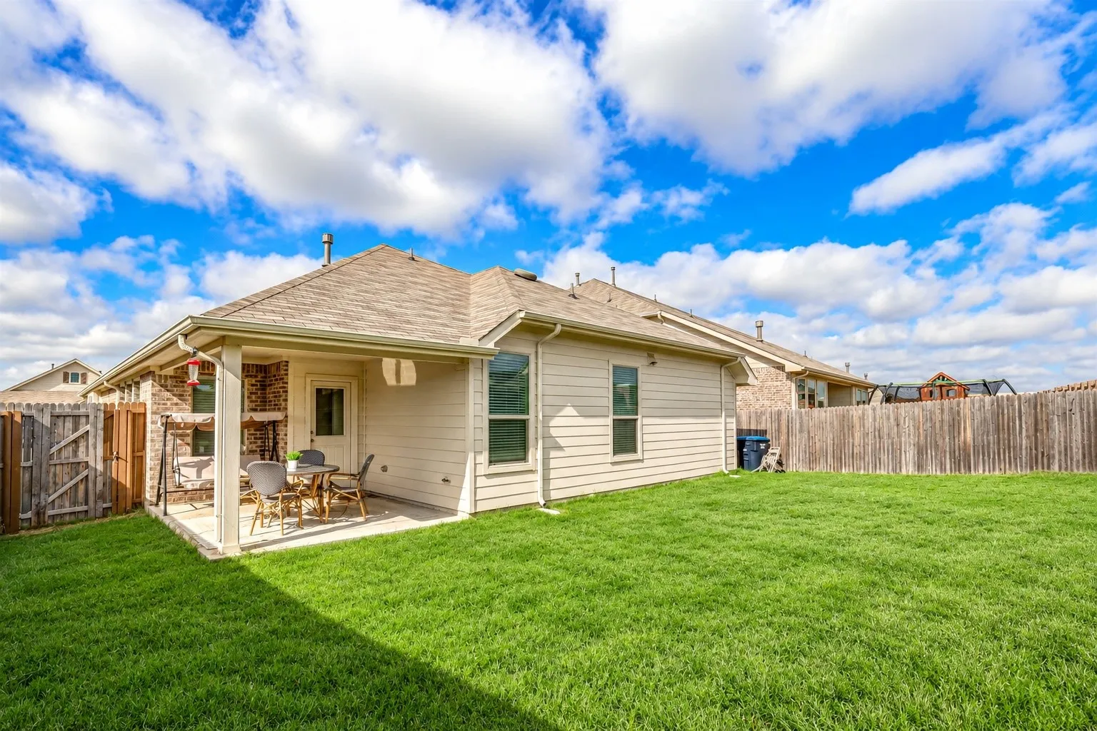 Expansive backyard featuring a covered patio, a privacy fence, and a well-maintained lawn