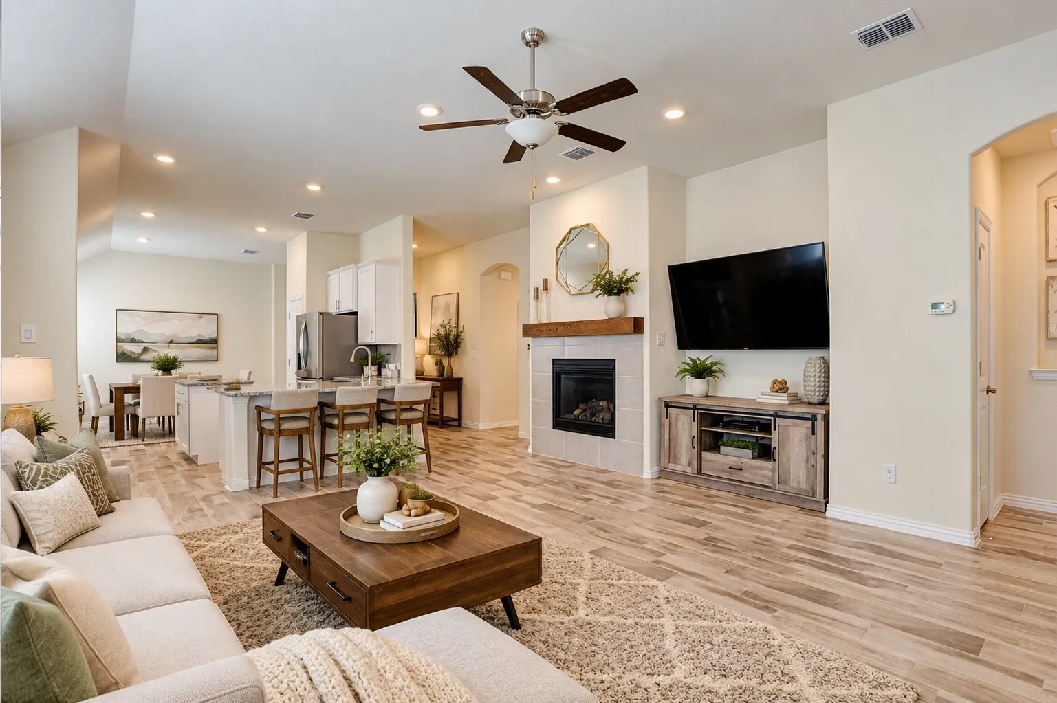 Living area featuring a fireplace with a wood mantle, wood-finish flooring, and a ceiling fan