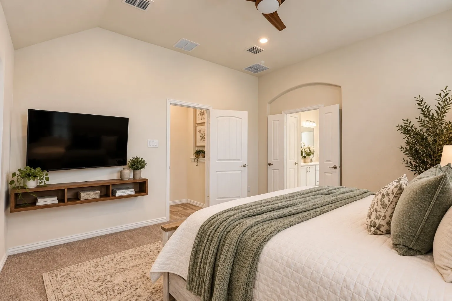 Vaulted ceiling, ceiling fan, recessed lighting, wood-finish floating media console, and an arched doorway