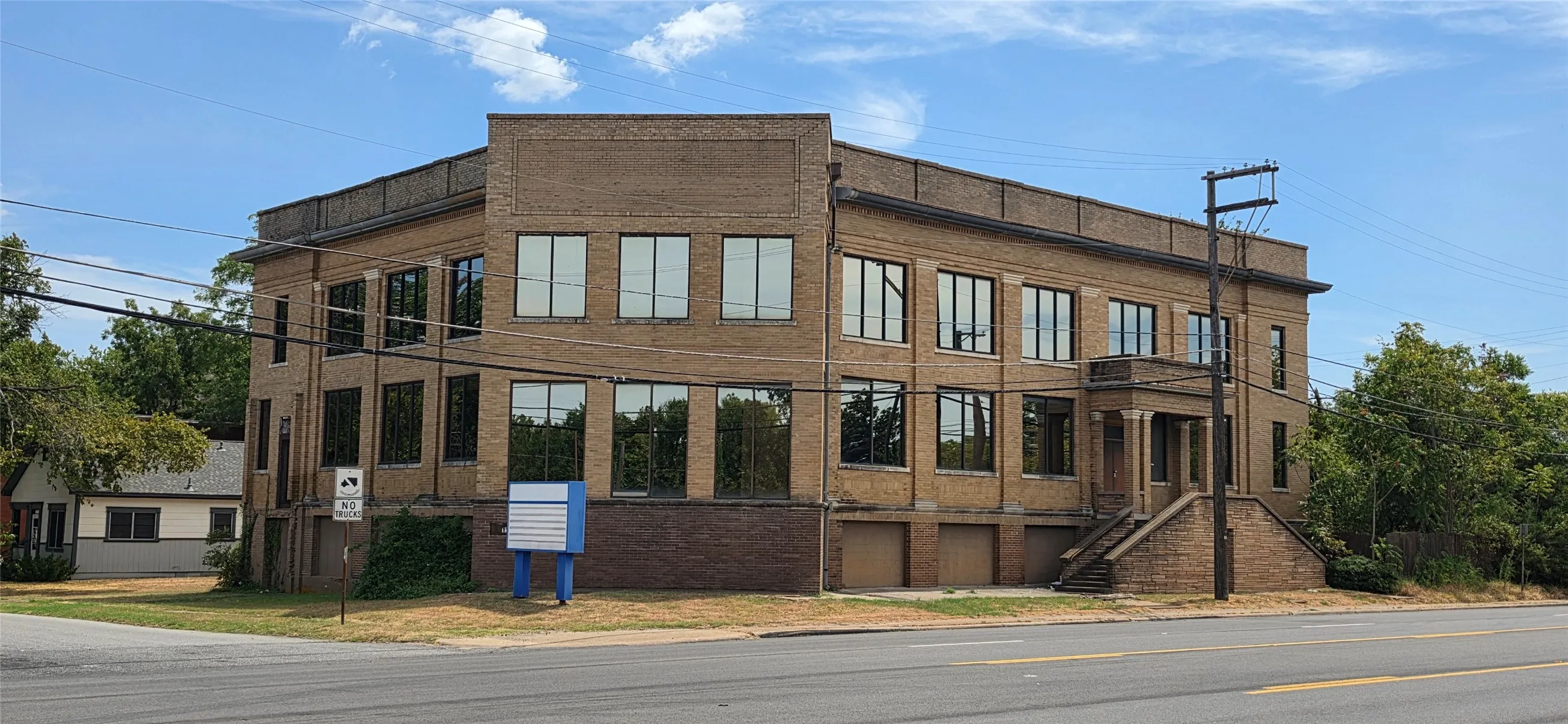 Brick exterior with multiple windows, prominent street frontage, and a raised entry with stone stairs