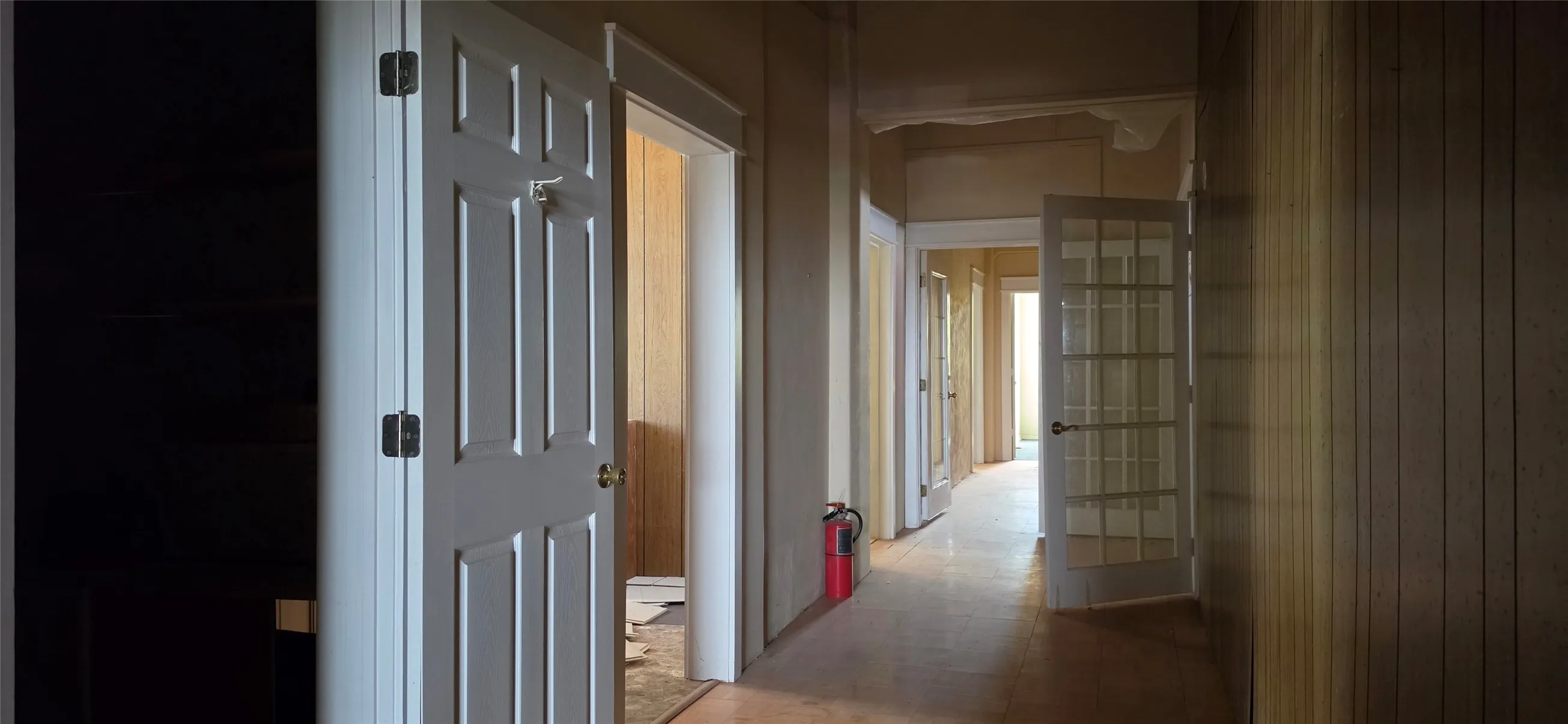 Hallway with wood-finish flooring, paneled walls, and multiple panel doors
