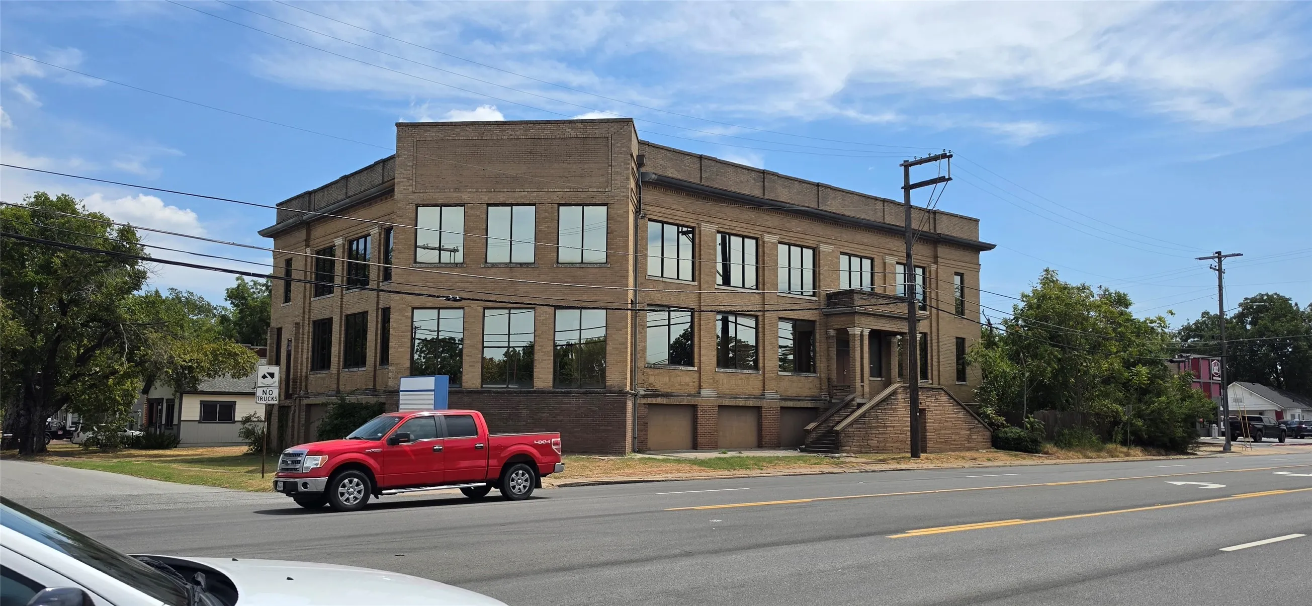 Brick exterior with extensive fenestration, elevated entry with staircase, and prominent corner presence