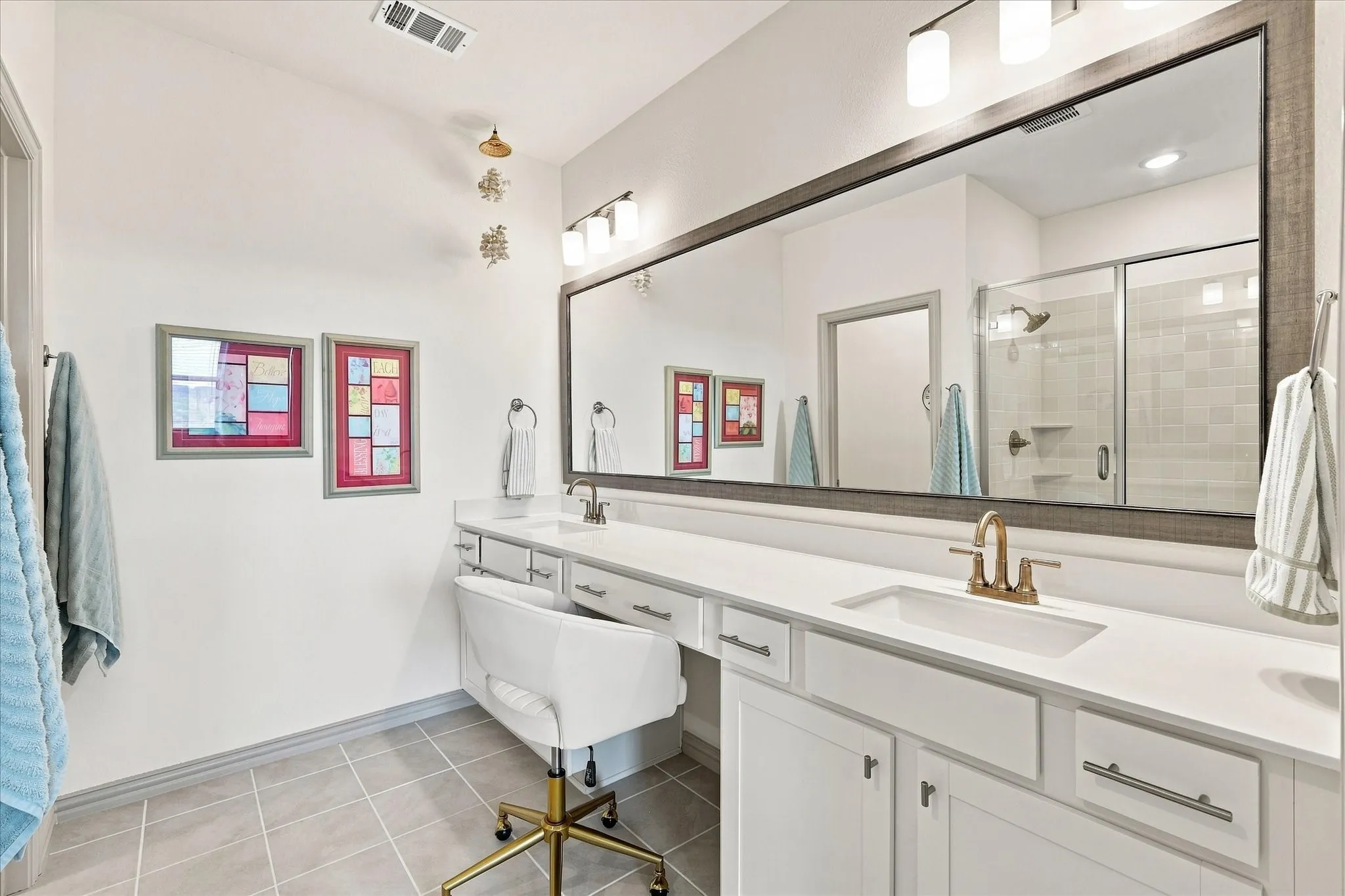 Modern white countertops with dual vanities and a seated make-up station.