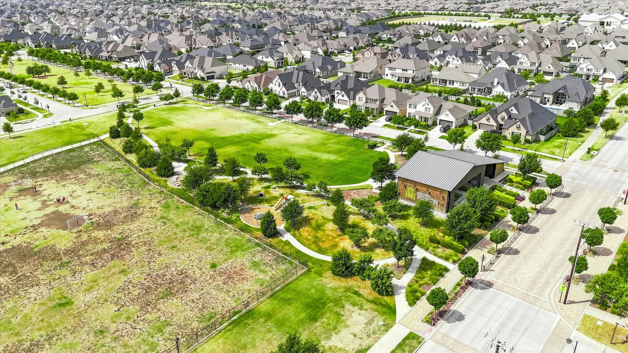 Community green space featuring a pavilion with a metal roof, landscaped grounds, and a paved pathway system