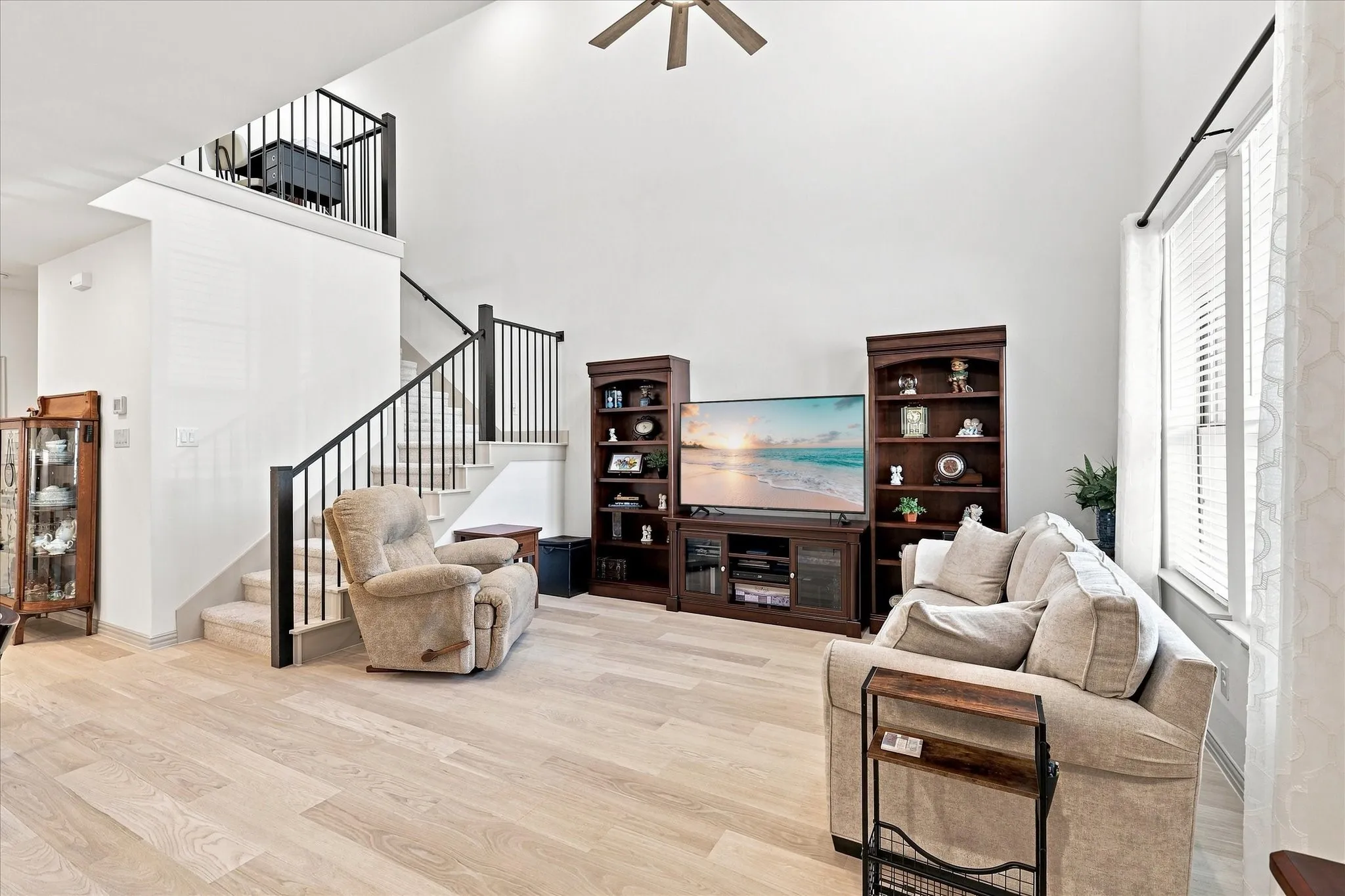 Ceiling fan and upper shades added to these soaring ceilings enhance the living room and allow neutral natural lighting.