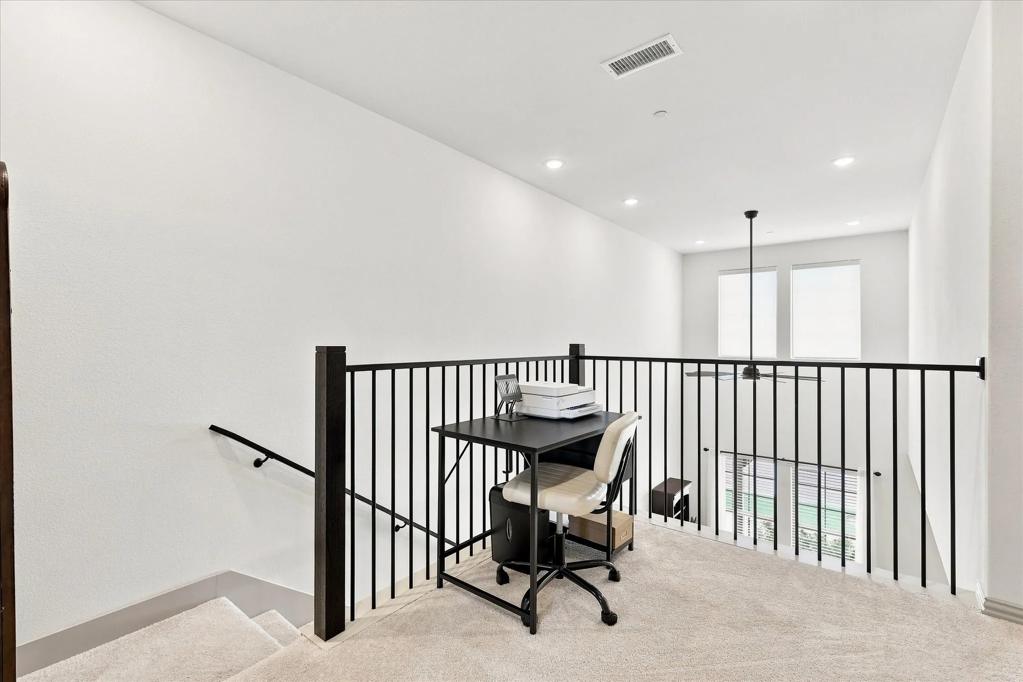 Open loft area featuring carpet flooring, dark metal railings, and recessed lighting.  Makes a perfect office or reading area.