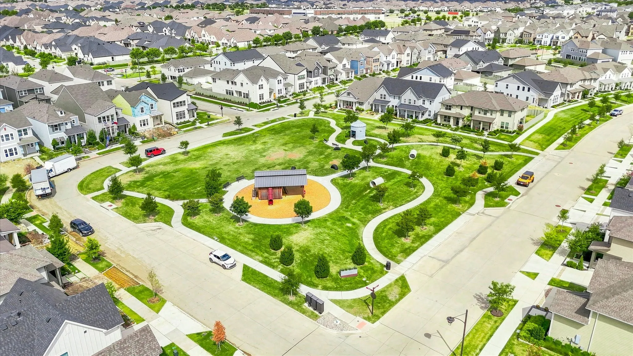 One of many expansive community parks featuring a playground, walking paths, and mature landscaping, surrounded by residential homes