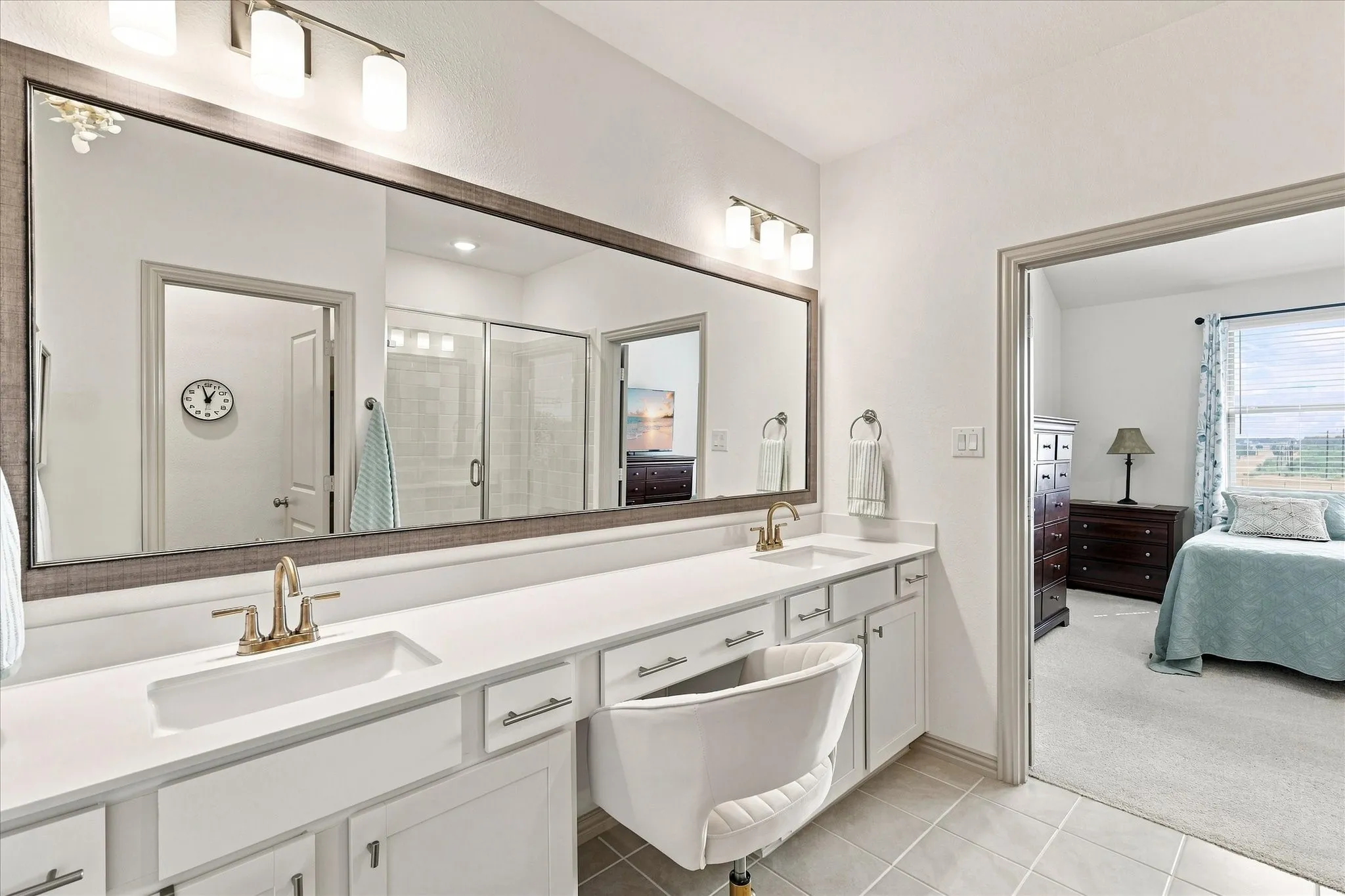 Dual vanity with white cabinetry, and a large framed mirror