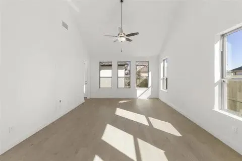 Vaulted ceilings, wood-finish flooring, ceiling fan, and multiple windows