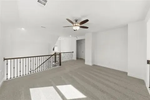Open loft space featuring light-toned carpeting and a ceiling fan with integrated lighting