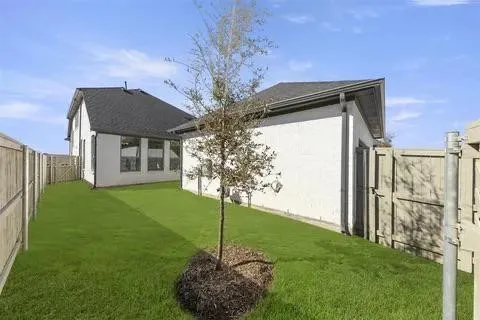 Expansive backyard with a manicured lawn, established tree, and full perimeter fencing