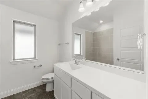 Bathroom featuring a single window, a built-in vanity with dual sinks, a large mirror, and a tiled shower enclosure