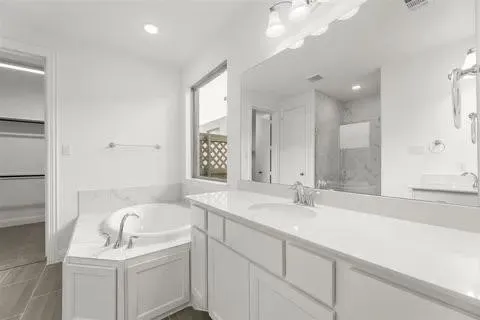 Built-in corner soaking tub with deck-mounted faucet, dual vanity with solid surface countertops, and an integrated walk-in shower