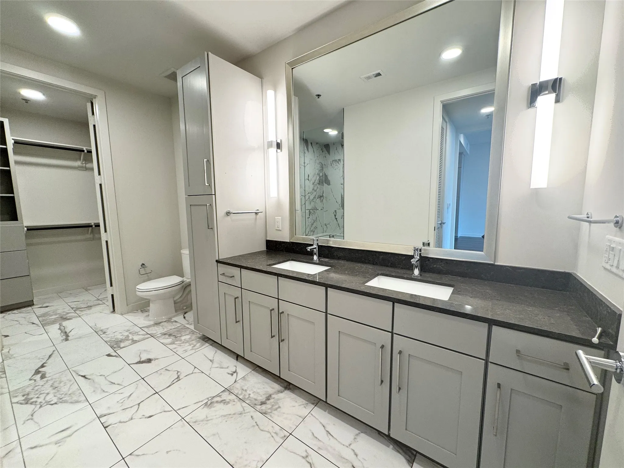 Bathroom featuring vanity, toilet, and a shower