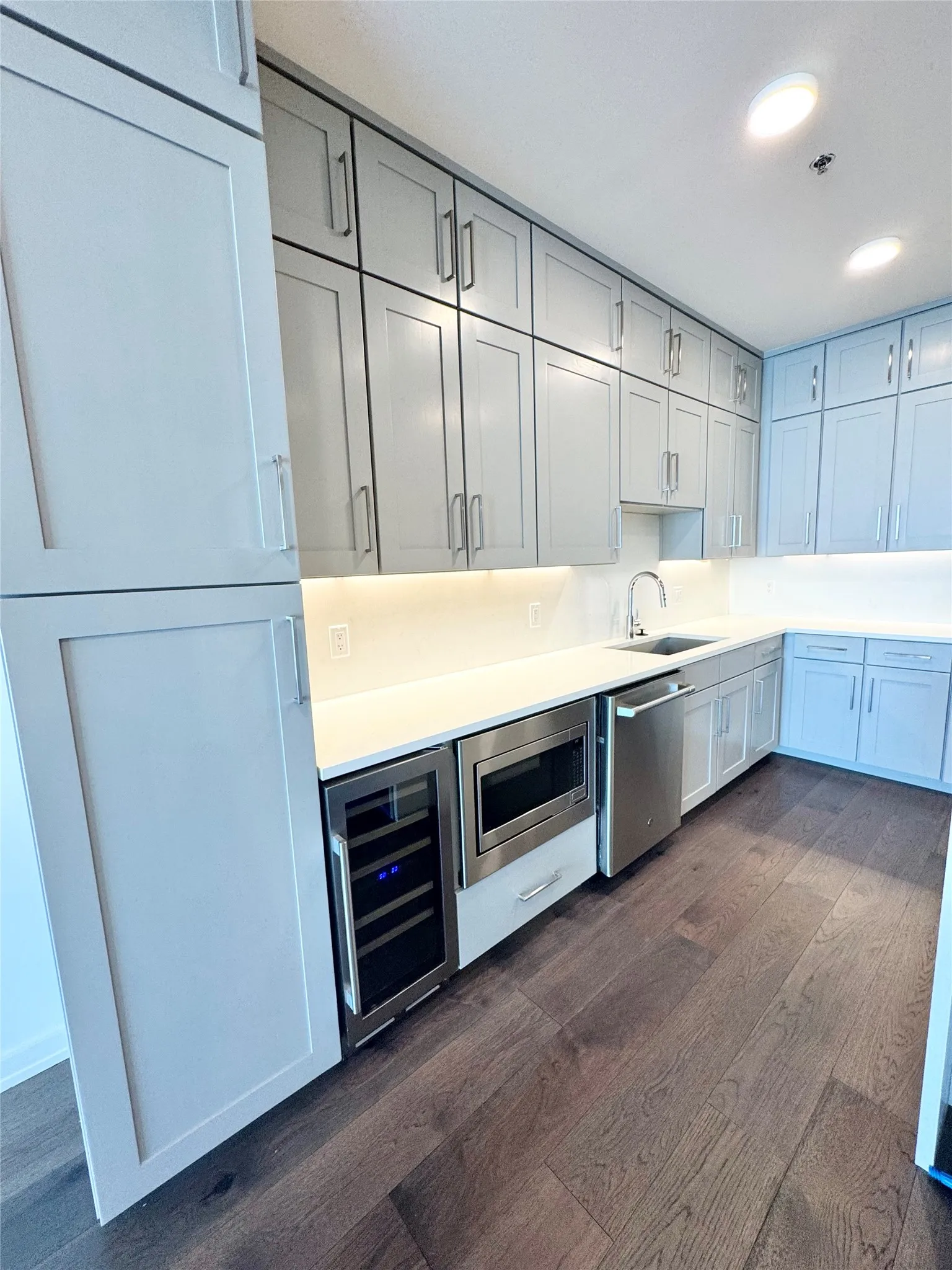 Kitchen with sink, gray cabinetry, dark hardwood / wood-style flooring, stainless steel appliances, and beverage cooler