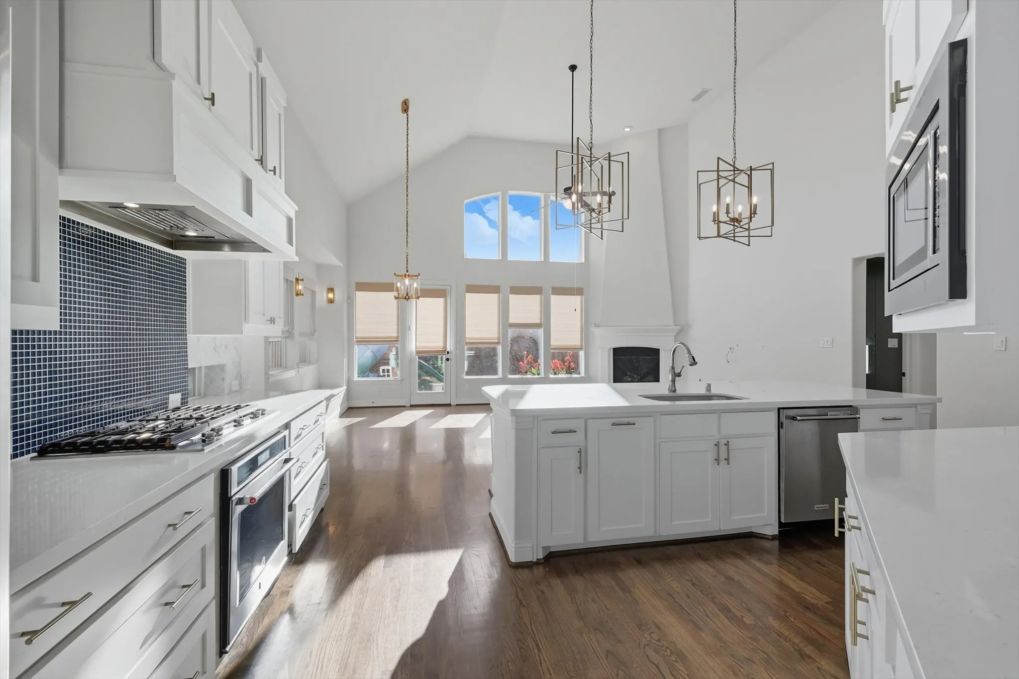 Kitchen featuring white cabinetry, high vaulted ceiling, decorative light fixtures, dark wood finished floors, and a chandelier