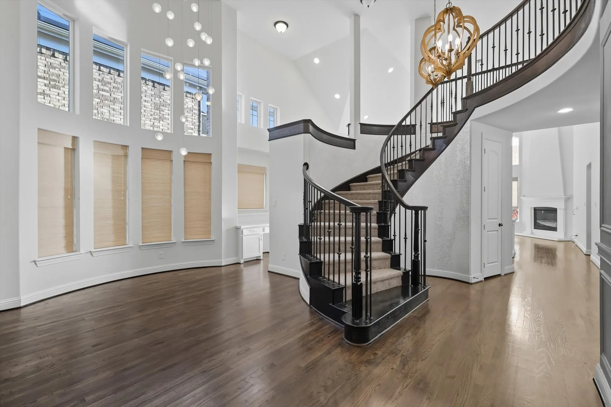 Entrance foyer with a chandelier, a high ceiling, dark wood-type flooring, a glass covered fireplace, and recessed lighting