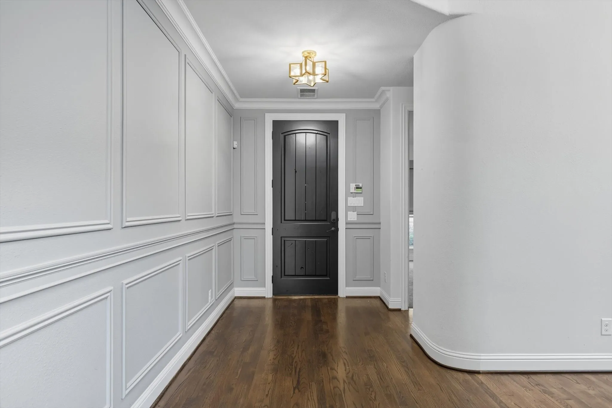Foyer entrance with dark wood-type flooring and crown molding