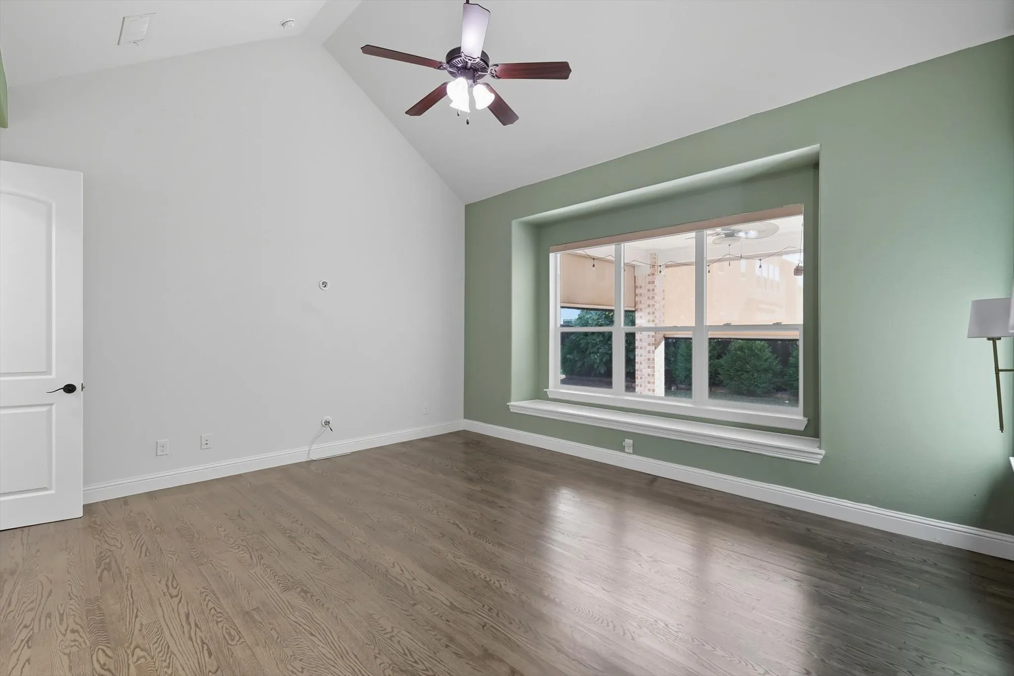 Unfurnished room featuring wood finished floors, ceiling fan, and high vaulted ceiling