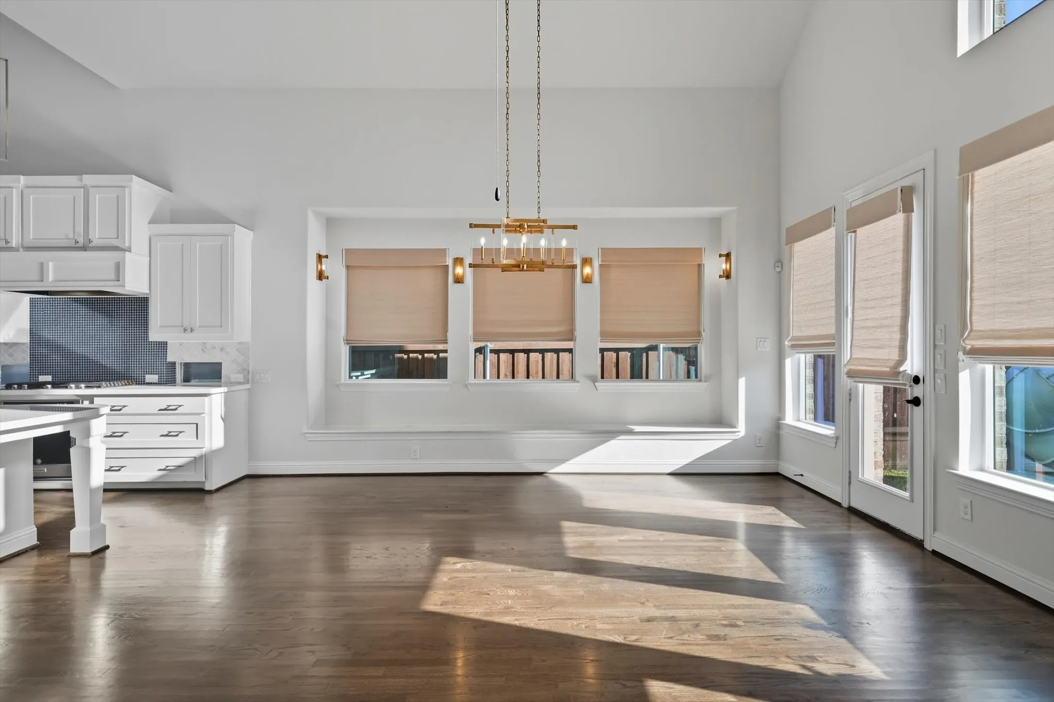Kitchen featuring dark wood-style flooring, white cabinets, light countertops, decorative backsplash, and hanging light fixtures