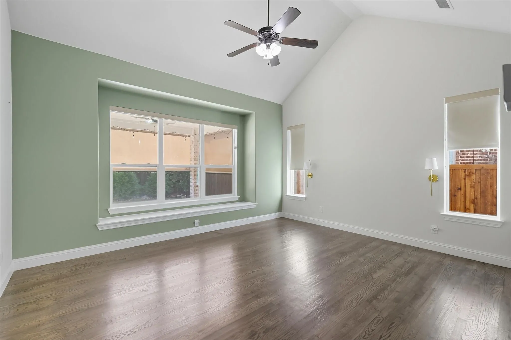 Spare room featuring high vaulted ceiling, dark wood-type flooring, and a ceiling fan