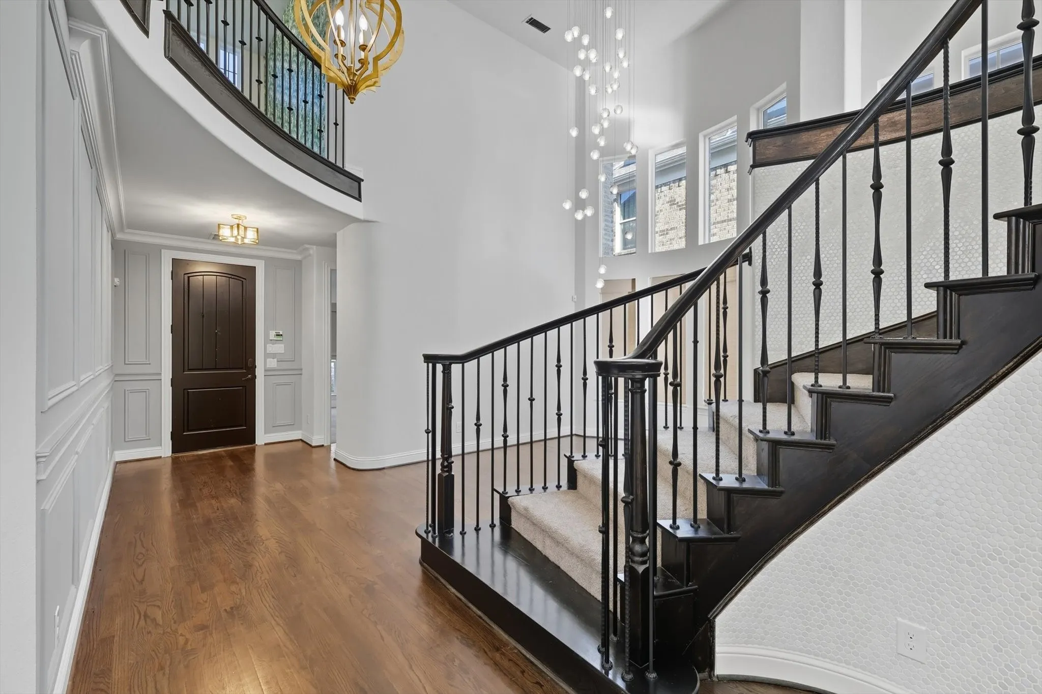 Entryway featuring a high ceiling, dark wood-style floors, a chandelier, and stairs