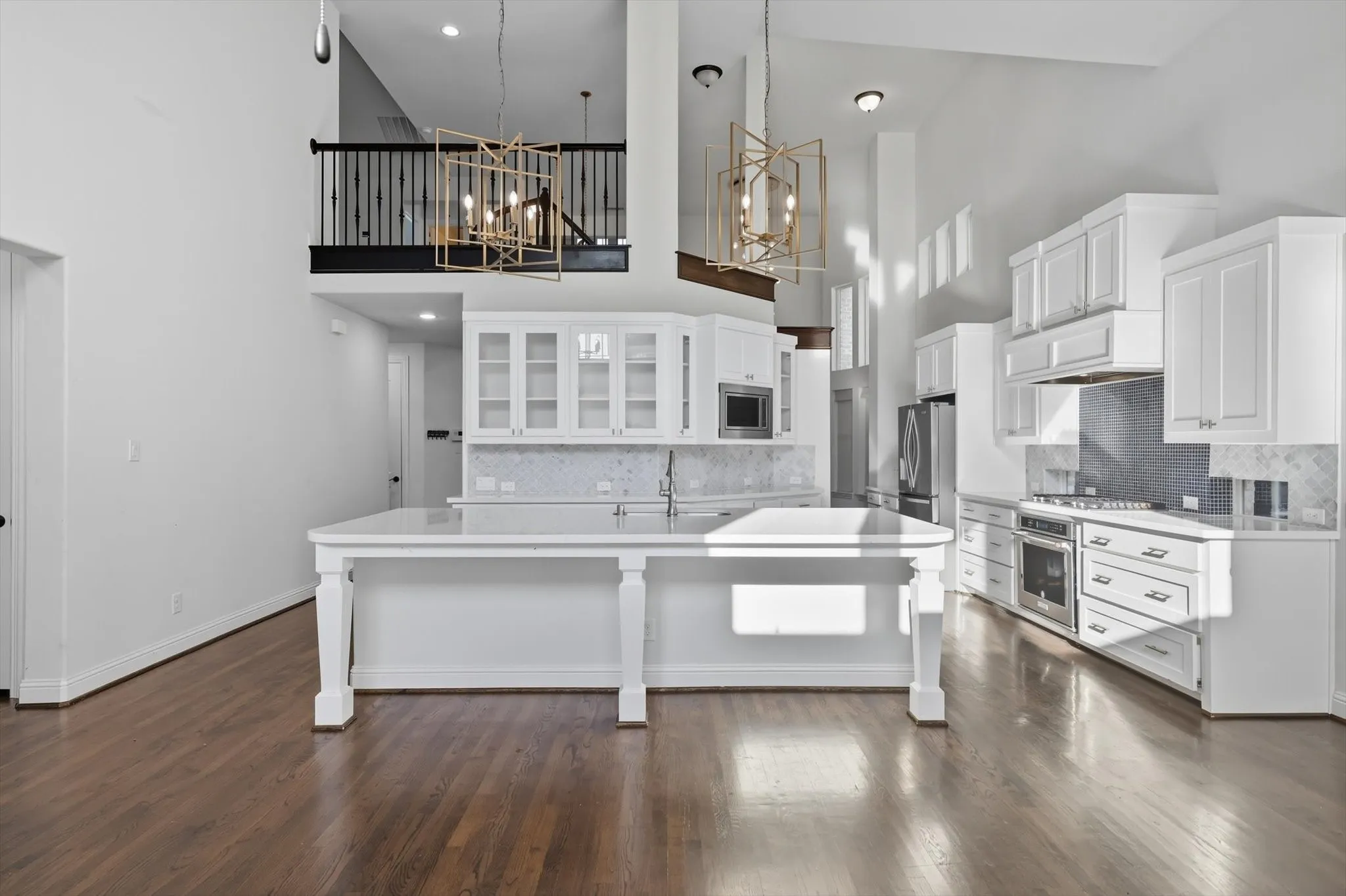 Kitchen featuring pendant lighting, white cabinets, dark wood-style flooring, a breakfast bar area, and a towering ceiling