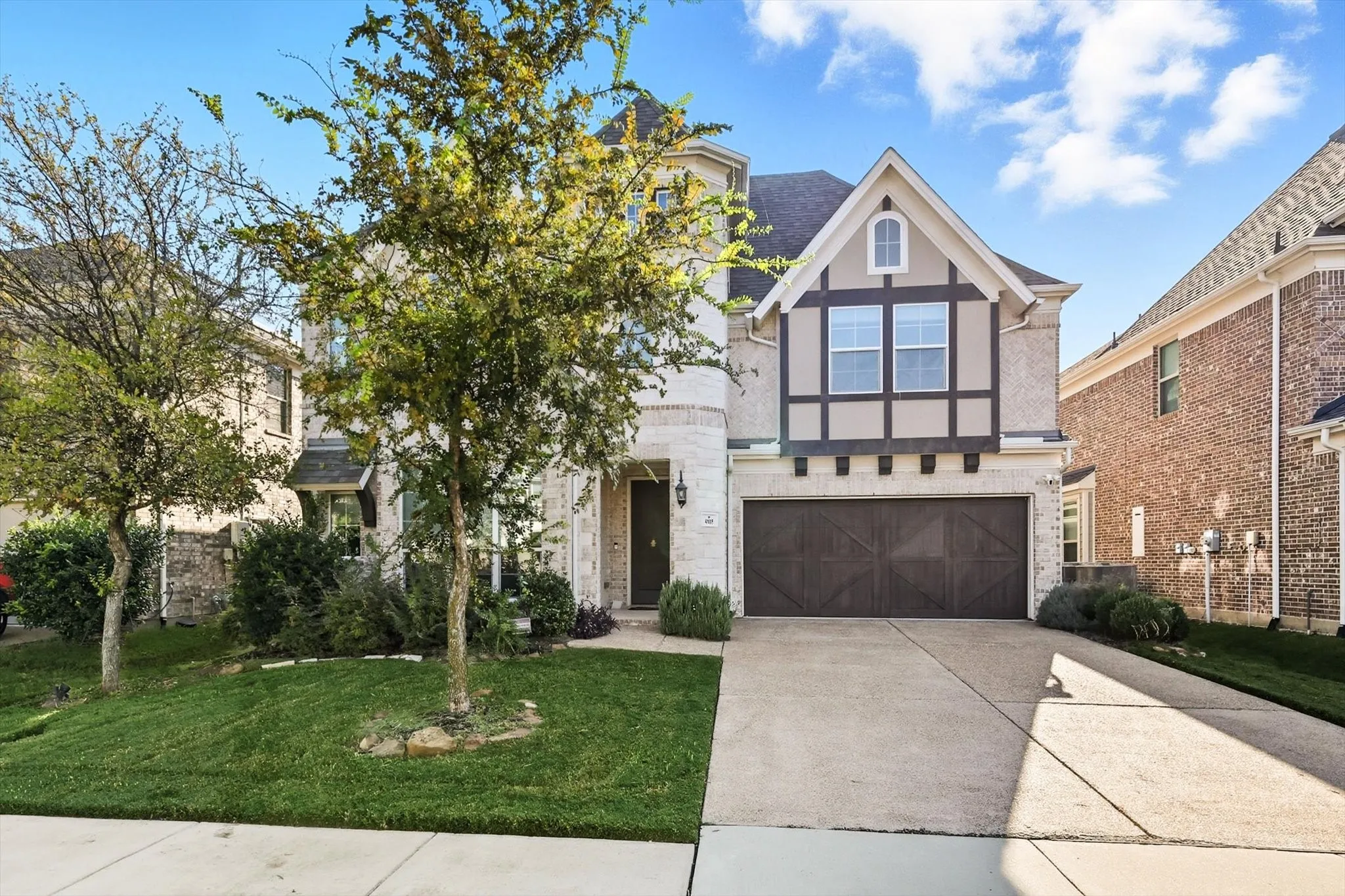 English style home with concrete driveway, stone siding, stucco siding, an attached garage, and a front yard